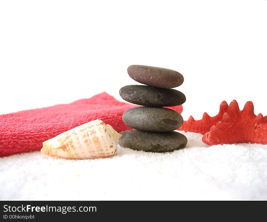 Spa essentials (pyramid of stones with white towel and seashell)