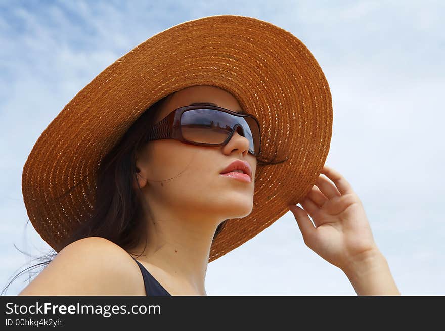 Portrait of young beautiful woman in straw hat and sunglasses