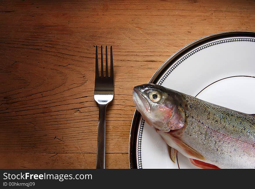 A trout on a plate with a fork. A trout on a plate with a fork.