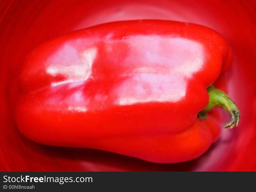 Bright red Bell Pepper against a red background.