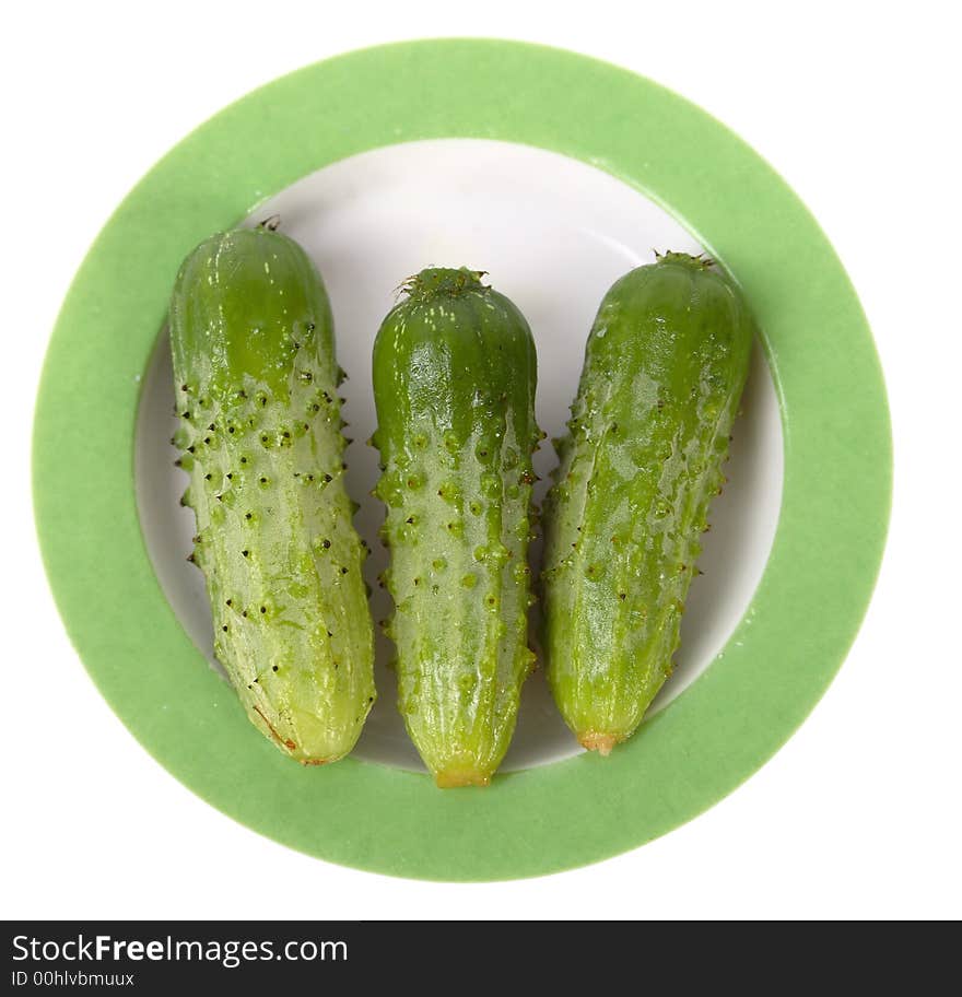 Three little cucumbers on a white saucer isolated