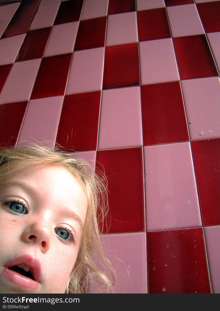 Cute blond little girl and a pink checkered wall as background