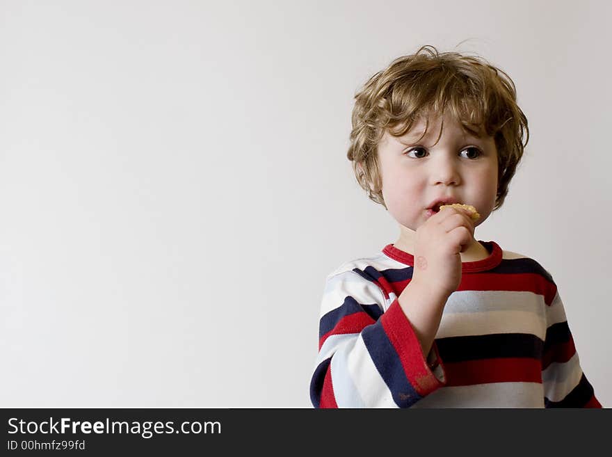 Child in striped shirt eating a cookie or biscuit. Child in striped shirt eating a cookie or biscuit