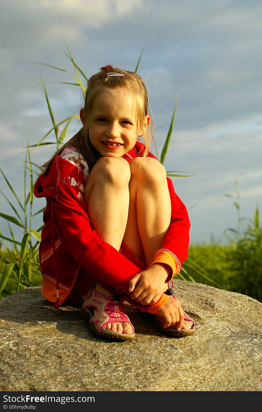 Smiling girl seat on stoun near sea. Smiling girl seat on stoun near sea