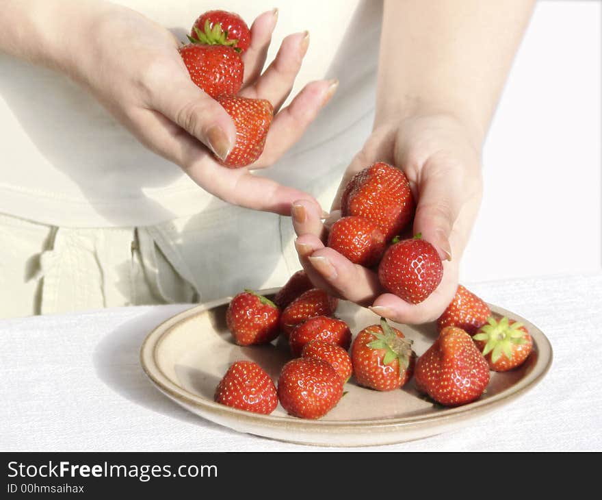 Hands of the girl a strawberry a ceramic plate a table a cloth white flax a background light. Hands of the girl a strawberry a ceramic plate a table a cloth white flax a background light