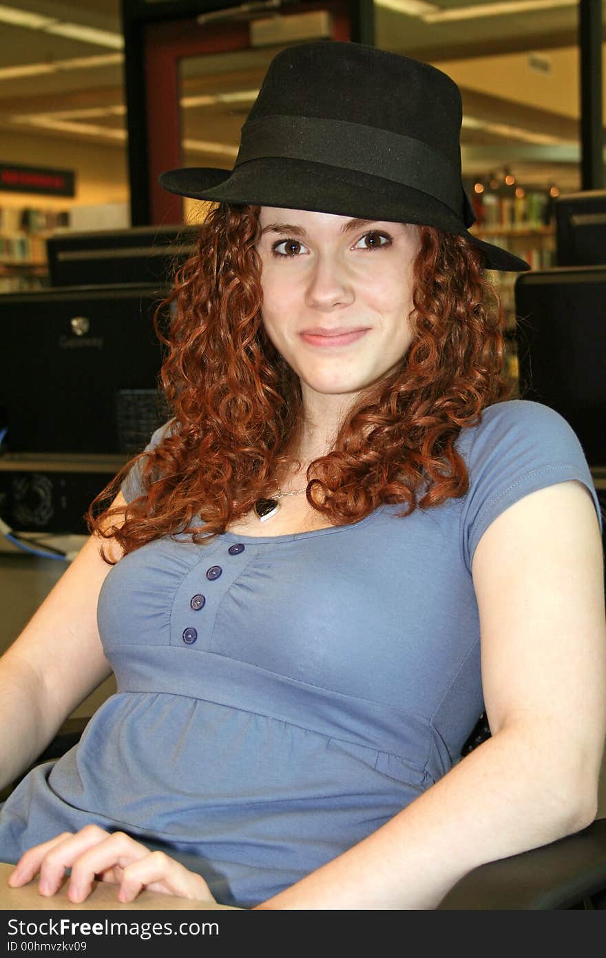 Cute red headed student with black hat taking a break from work. Cute red headed student with black hat taking a break from work