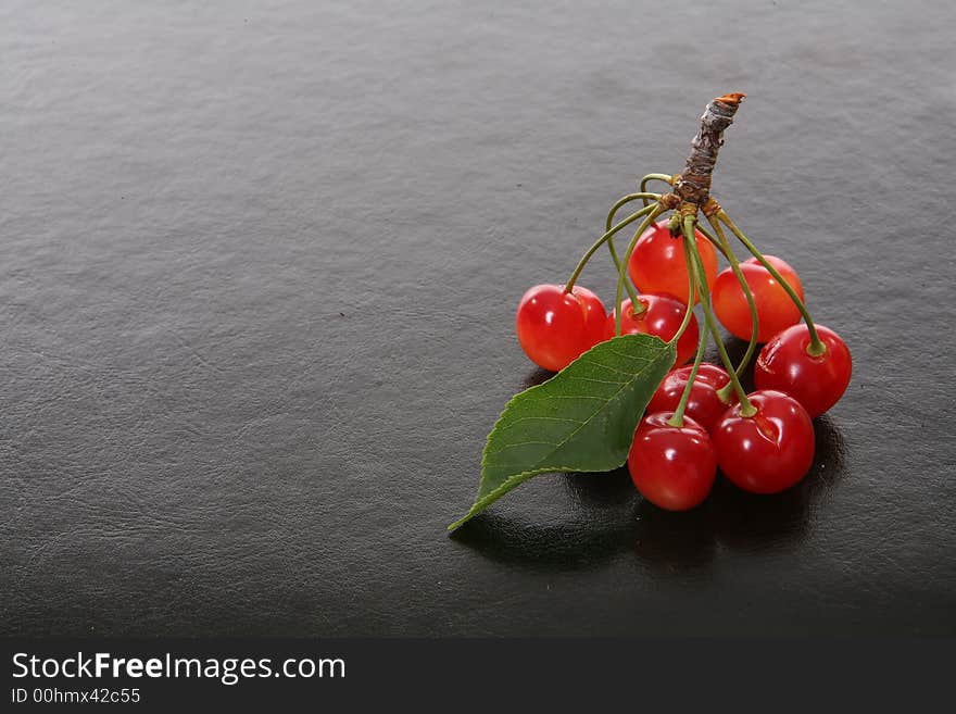 Bright colorful fresh cherries over a black texteure