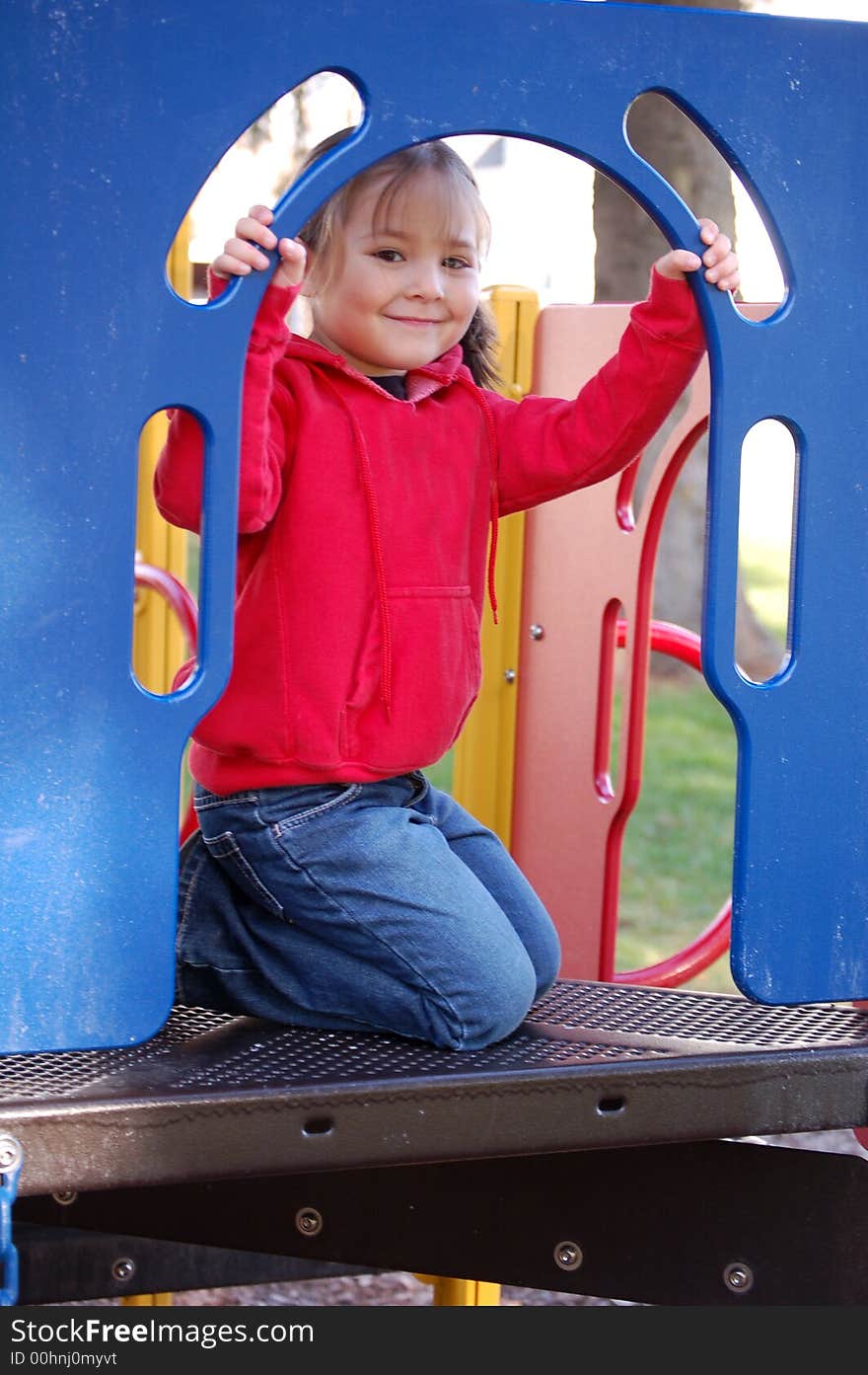 Smiling four year old girl in red sweatshirt playing on a playground. Smiling four year old girl in red sweatshirt playing on a playground.