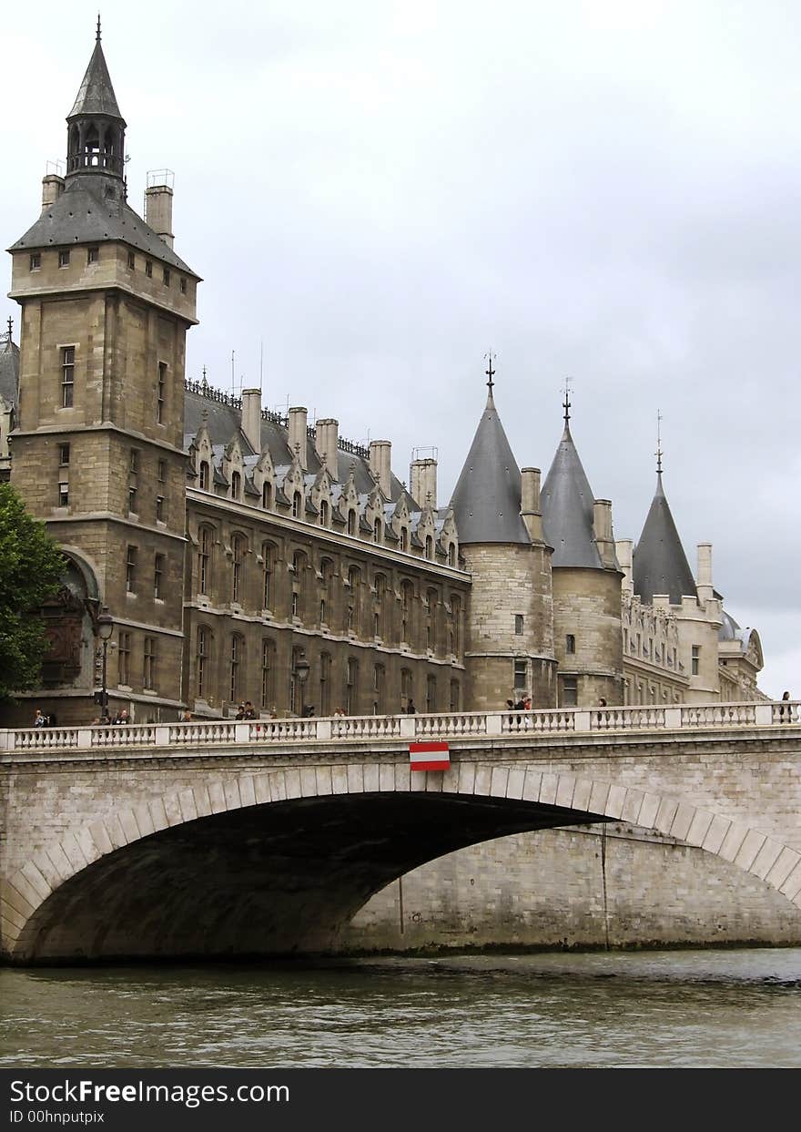 View of the Conciergerie and bridge from the Seine River in Paris, France, in gray misty light. View of the Conciergerie and bridge from the Seine River in Paris, France, in gray misty light.