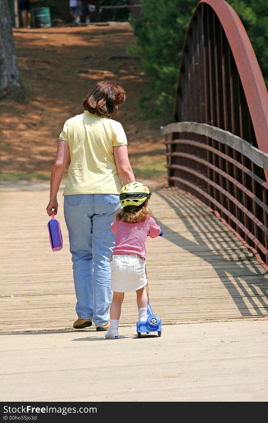 A mother and girl on skates crossing a bridge. A mother and girl on skates crossing a bridge