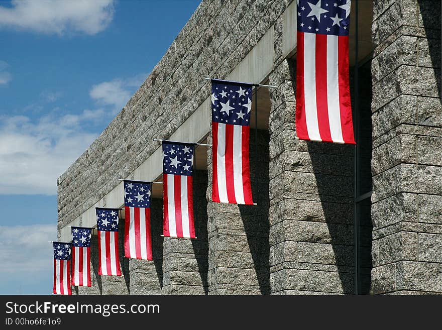 Seven red, white and blue flags handing over the windows of a gray block building. Seven red, white and blue flags handing over the windows of a gray block building.