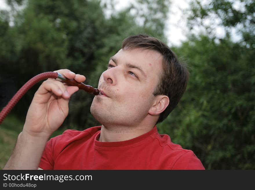 Man in red smokes a hookah outdoor