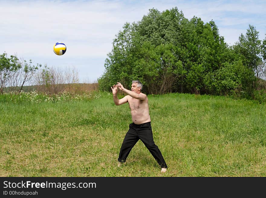 The man plays with a ball outdoor in the summer. The man plays with a ball outdoor in the summer