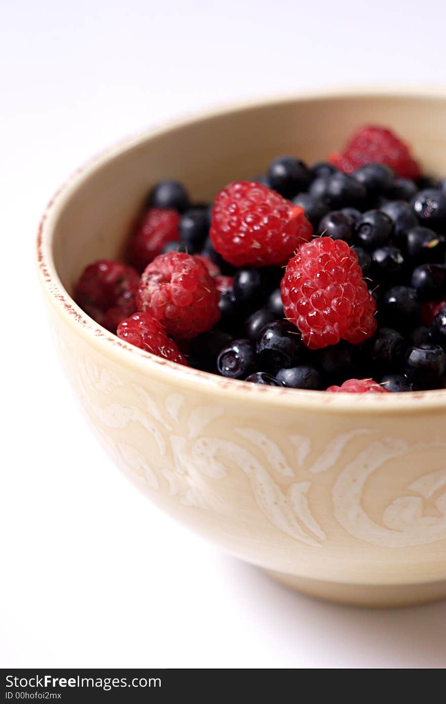 Bowl of fresh forest raspberry and blueberry, focus on raspberries