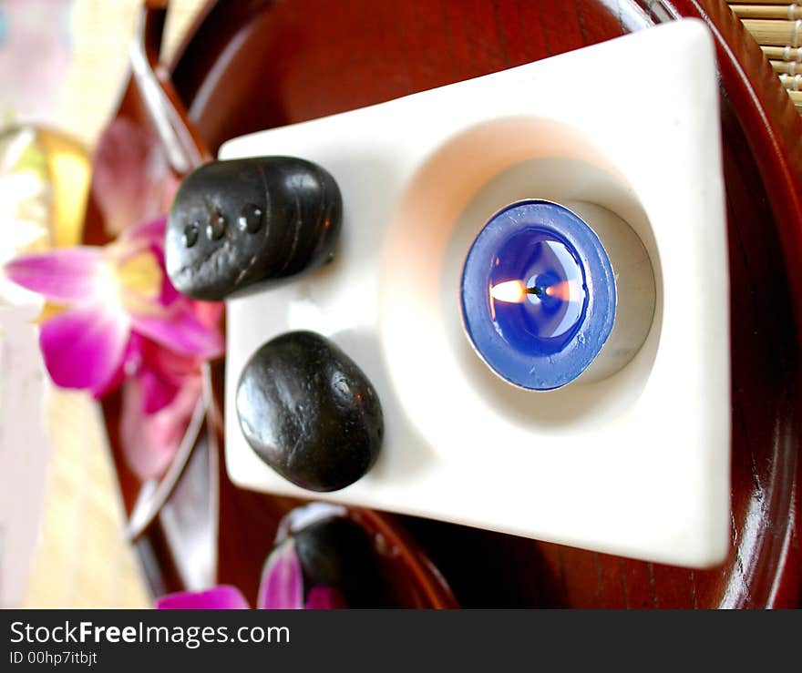 Aromatic candle, stones, orchid in a wooden tray