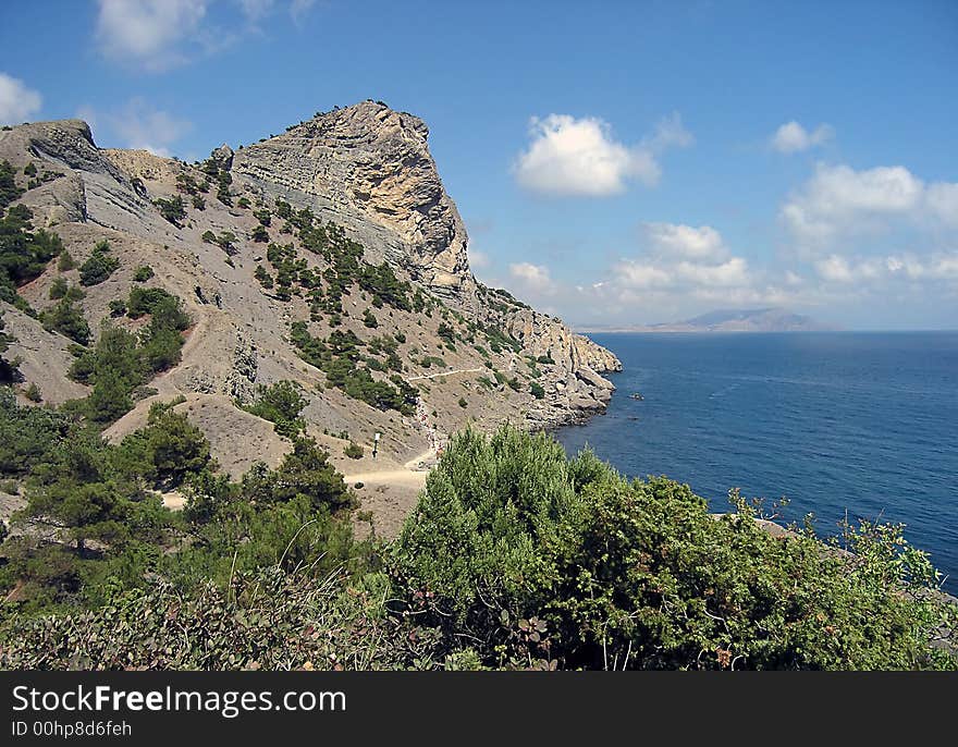 Big rocky mountains, sea and sky with white clouds. Big rocky mountains, sea and sky with white clouds