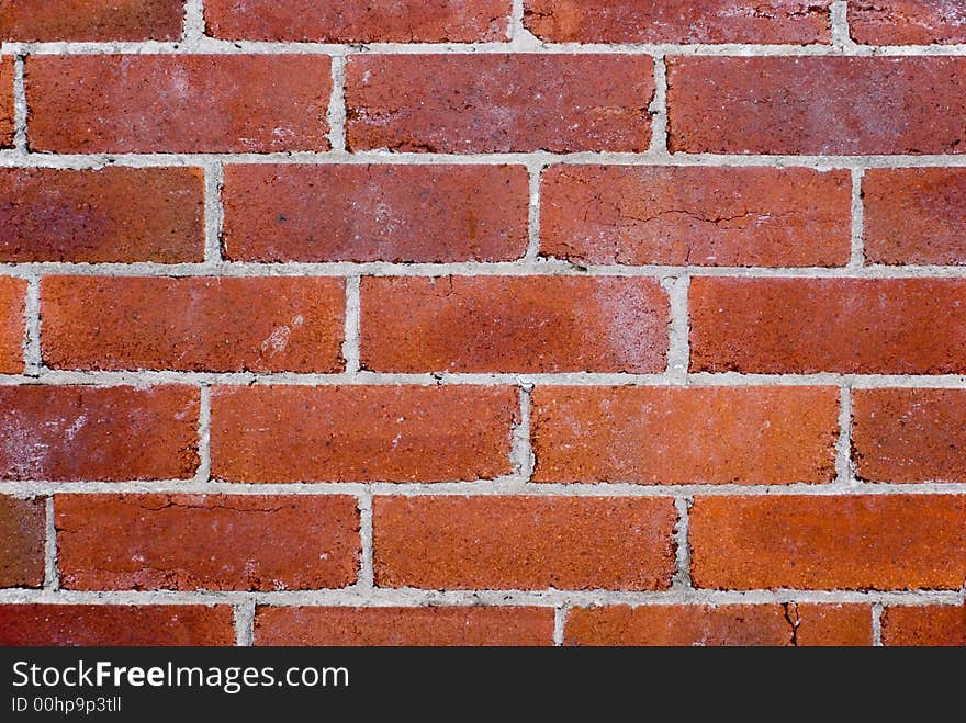 An old red brick wall, some cracks, with grey white mortar close up