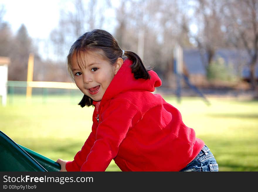 Four year old girl climbing up a slide at the playground. Four year old girl climbing up a slide at the playground.