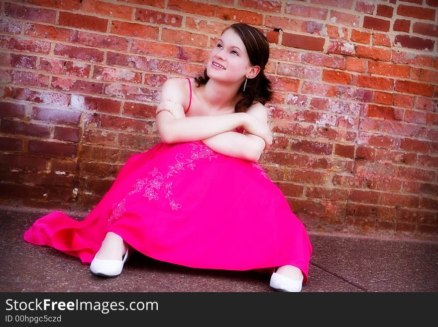 Beautiful, smiling teen in formal wear gazing up from the sidewalk by an old brick wall. Beautiful, smiling teen in formal wear gazing up from the sidewalk by an old brick wall.