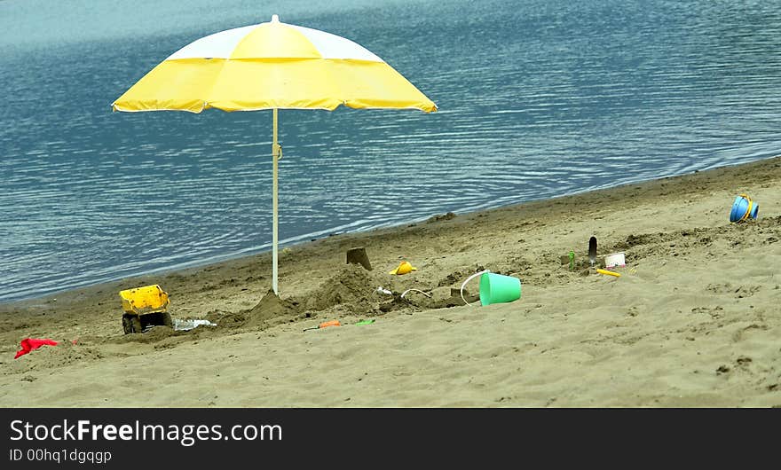 Yellow beach umbrella with scattered sand toys