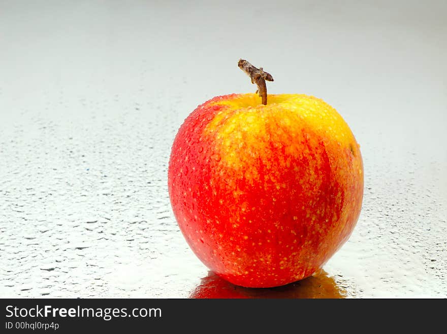 Red apple on  surface of  water covered with drops