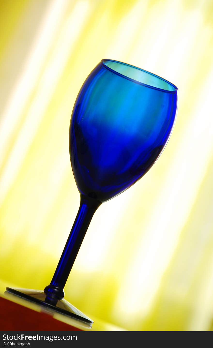 Blue cobalt wine glass on yellow background