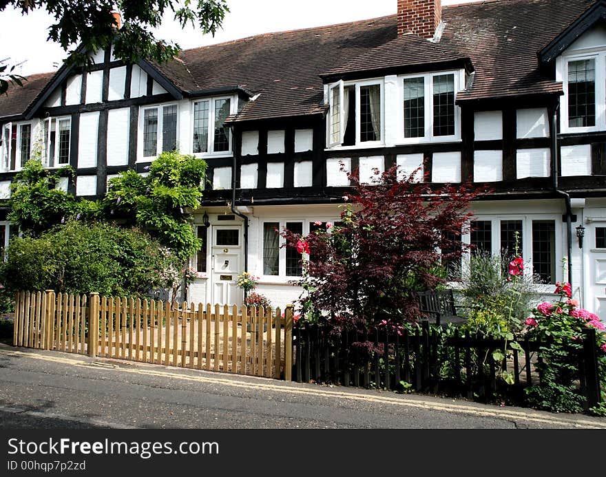 Row of Timber Framed English Village Cottages with a picket fence in front. Row of Timber Framed English Village Cottages with a picket fence in front.