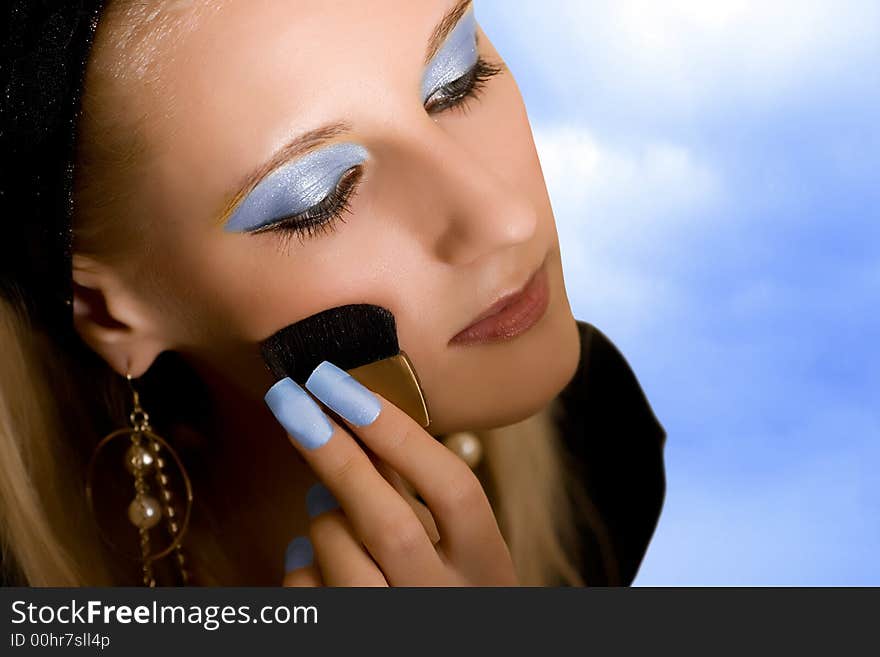 Portrait of young beautiful girl with brush on sky background