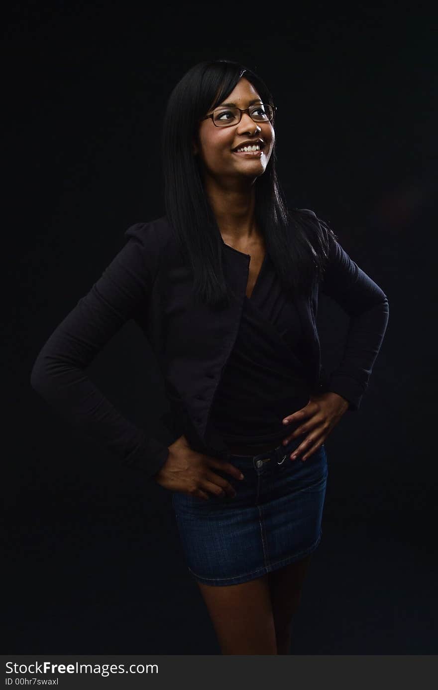 African America woman wearing glasses, black jacket and top with a denim mini skirt.  She is smiling with her hands on her hips. African America woman wearing glasses, black jacket and top with a denim mini skirt.  She is smiling with her hands on her hips.