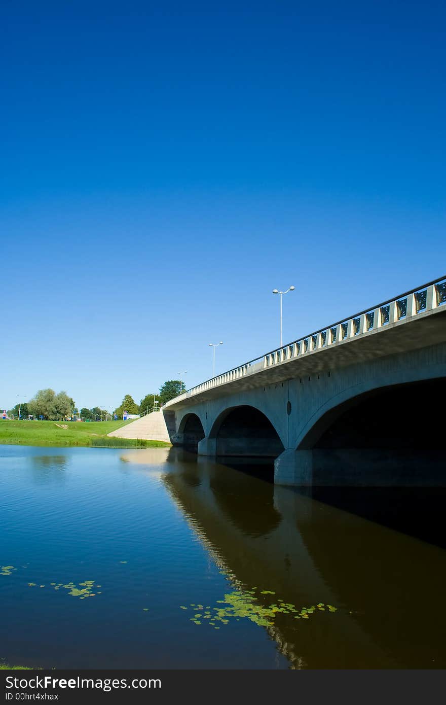 Bridge. Reflection in river. Blue sky.