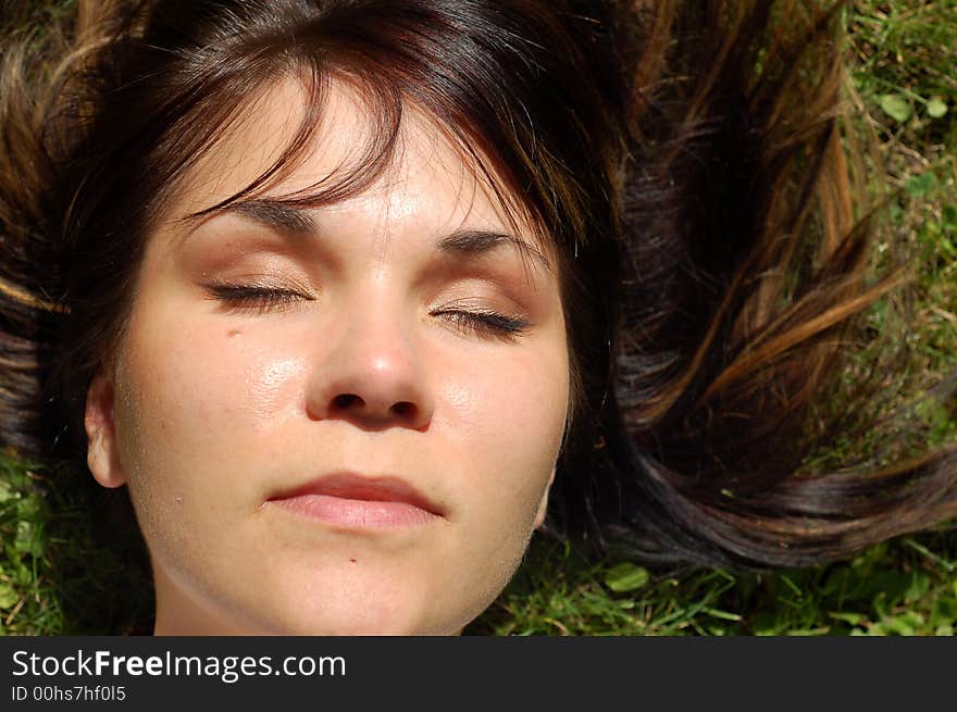 Attractive woman lying and relaxing on green grass. Attractive woman lying and relaxing on green grass