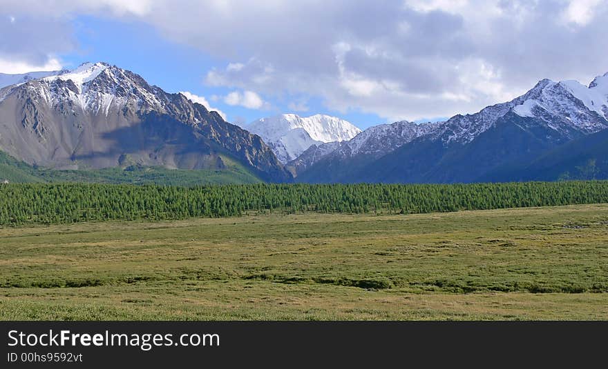 There is fine mountain valley framed by mountains which are covered with a snow. There is fine mountain valley framed by mountains which are covered with a snow.