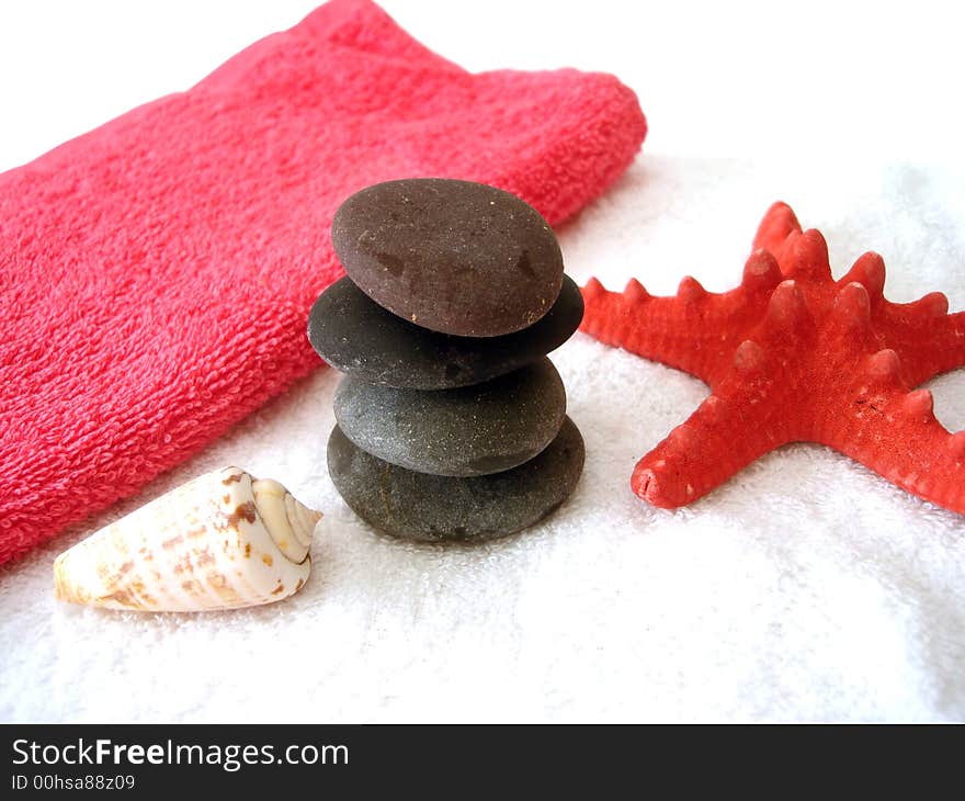 Spa essentials (pyramid of stones with white towel and seashell)