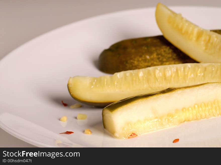 Kosher dill pickle spears on a white plate with a gray background