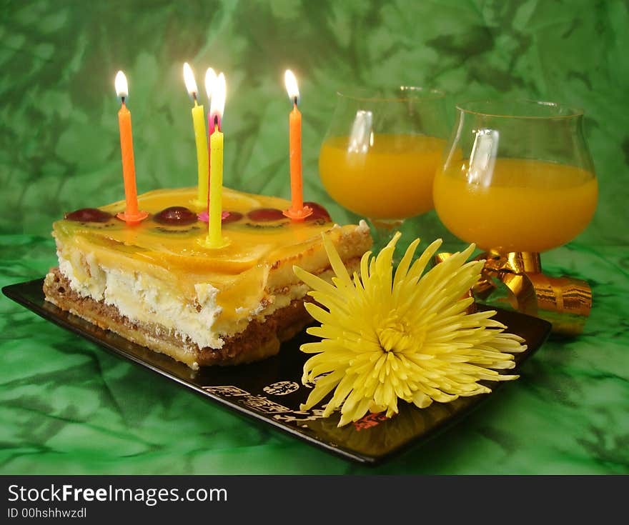 Celebratory table (cake and candles, two glasses) on green