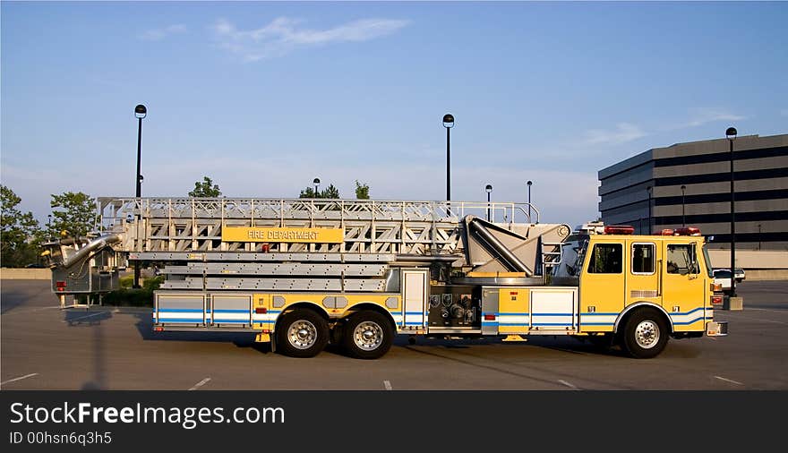 This is a side view of a fire truck with ladders and a bucket used for reaching fires in high places. This is a side view of a fire truck with ladders and a bucket used for reaching fires in high places.