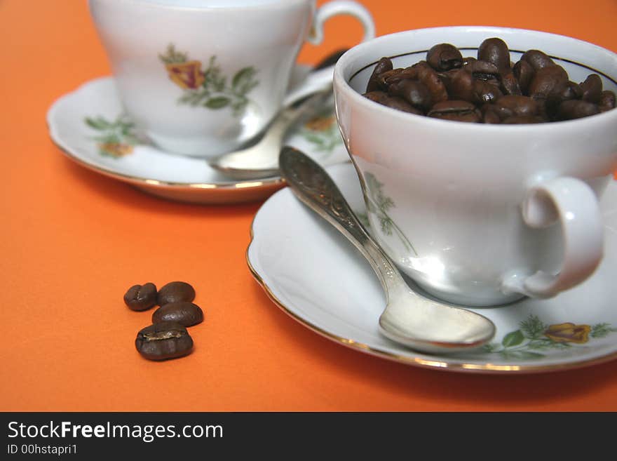 Grains of coffee and cup on an orange background