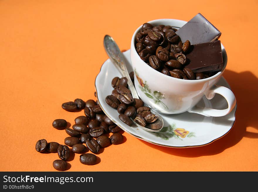 Grains of coffee and cup on an orange background