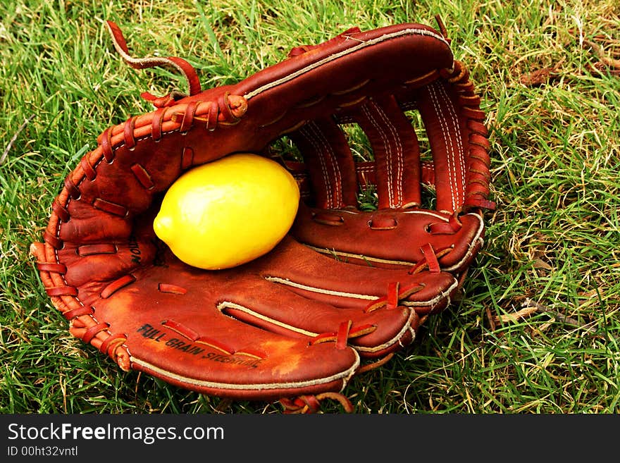 Grassy patch where an old Baseball Mitt holds a lemon inside. Grassy patch where an old Baseball Mitt holds a lemon inside