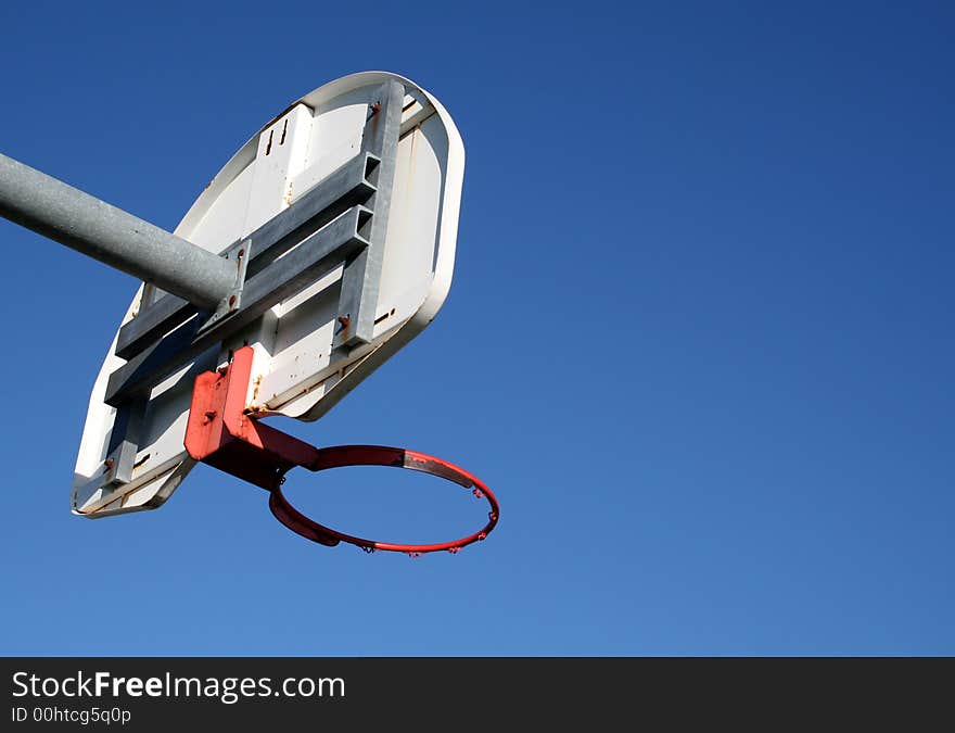 A playground basketball hoop against a blue sky. A playground basketball hoop against a blue sky.