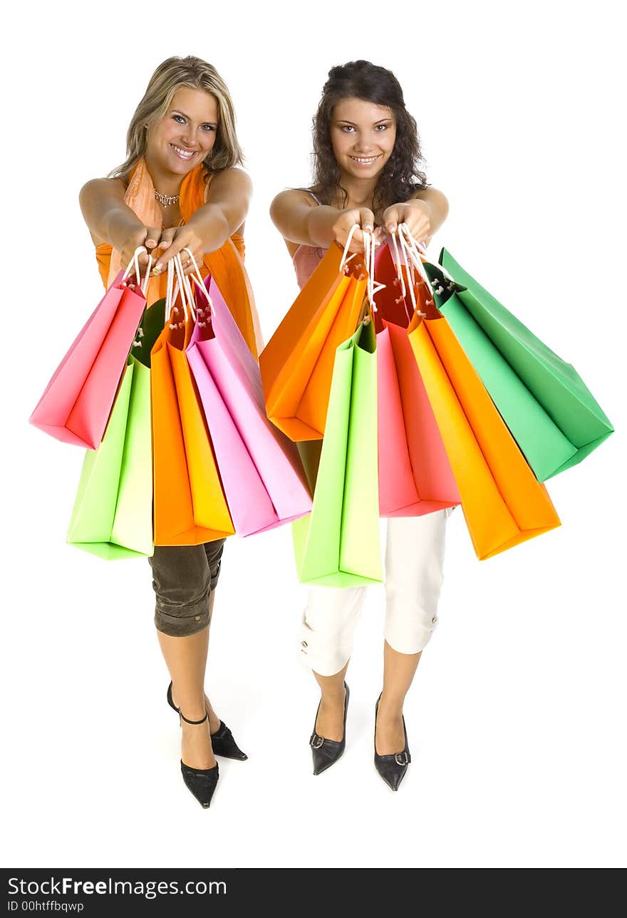 Two beautiful, young woman standing and holding bags. Womans are giving bags to somebody. Isolated on white in studio. Whole body. Two beautiful, young woman standing and holding bags. Womans are giving bags to somebody. Isolated on white in studio. Whole body