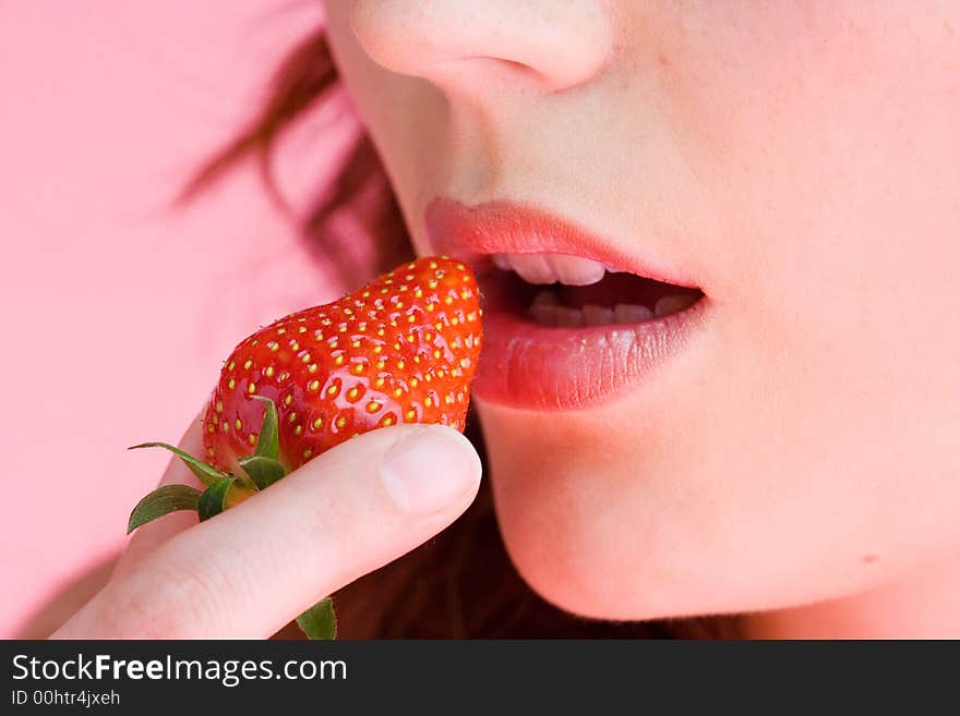 One young, beautiful woman eats a strawberry. One young, beautiful woman eats a strawberry