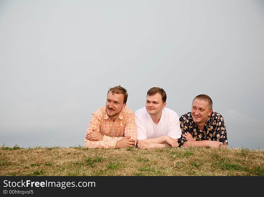 Three men, laying on the grass