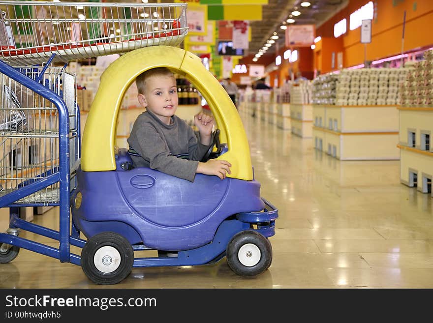 Child in the toy automobile in the supermarket