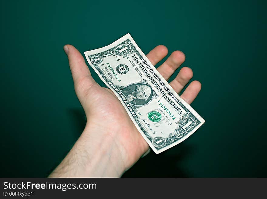 One paper dollar on a male's left palm. One paper dollar on a male's left palm