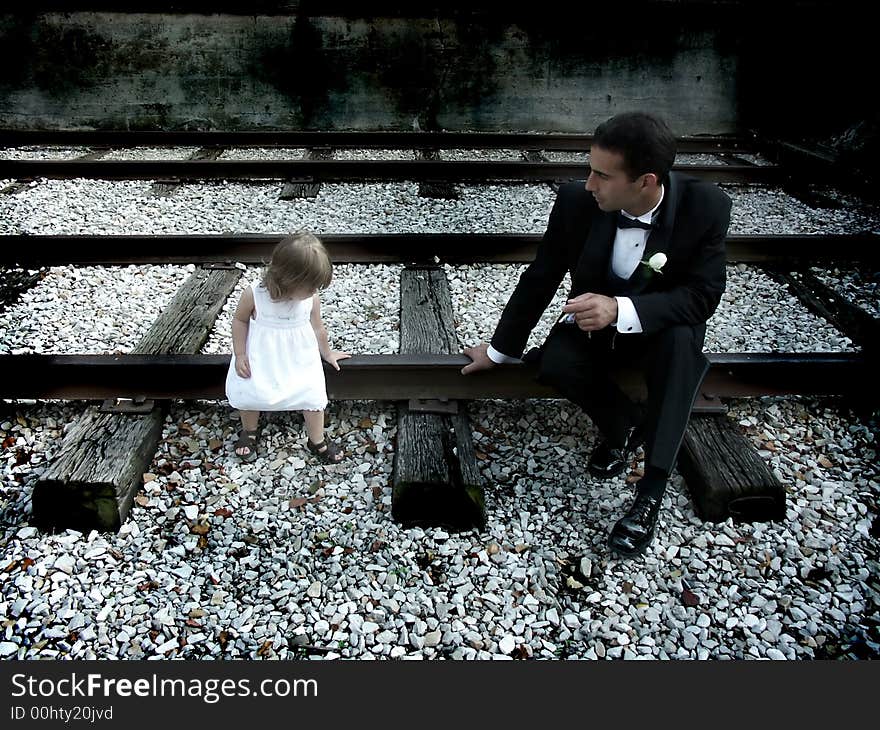 A father and daughter sitting on railroad tracks. A father and daughter sitting on railroad tracks