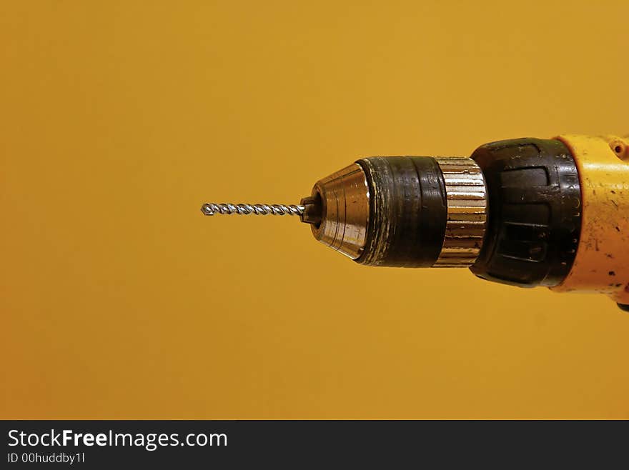 Old yellow drill with new cement drill bit against yellowish background. Old yellow drill with new cement drill bit against yellowish background