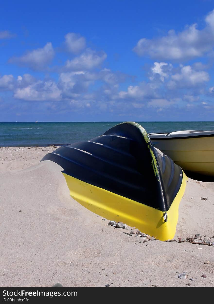 A Yellow on black rowboat on a beach in Tidsvideleje. A Yellow on black rowboat on a beach in Tidsvideleje