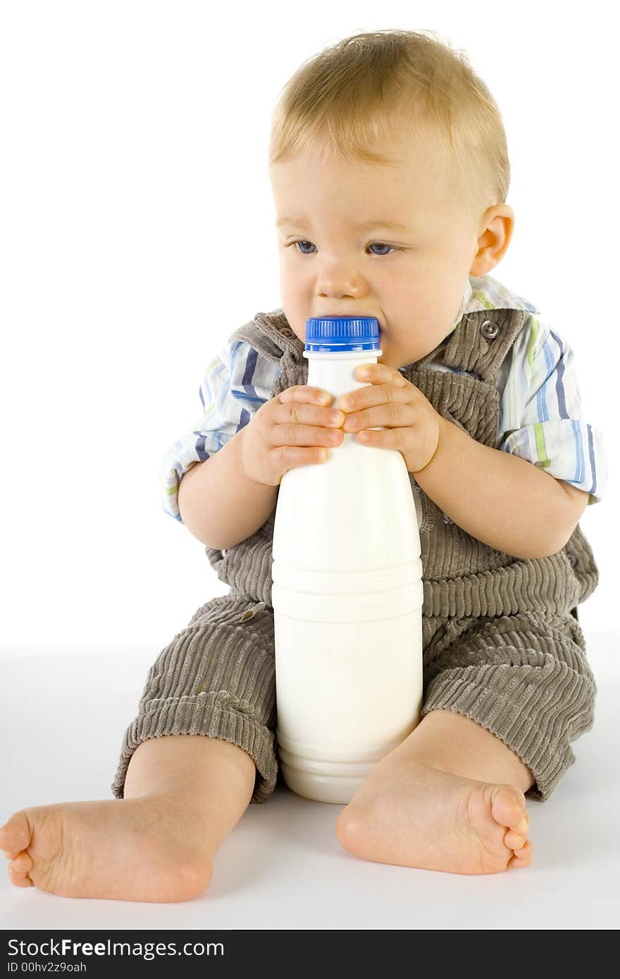 Little baby boy sitting on the floor. Holding and biting a bottle of milk. Whole body. Little baby boy sitting on the floor. Holding and biting a bottle of milk. Whole body