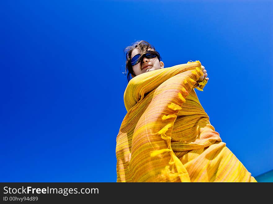 Beautiful young girl wrapped in yellow scarf against clear blue sky. Beautiful young girl wrapped in yellow scarf against clear blue sky.